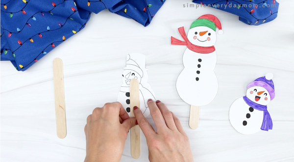 hand taping popsicle stick to back of snowman