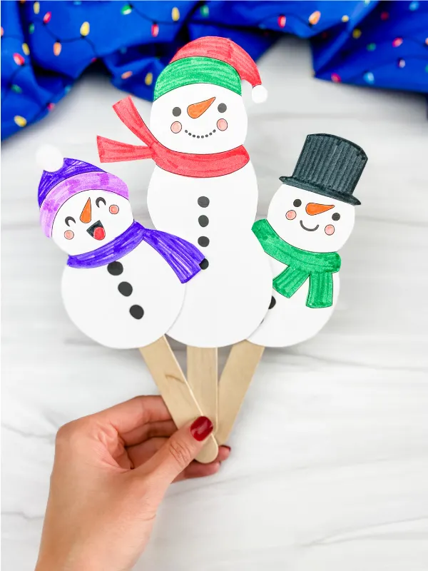 hand holding snowman stick puppets