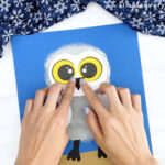 hand gluing beak onto snowy owl craft