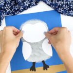 hand gluing face onto snowy owl craft