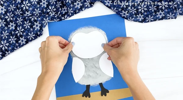 hand gluing face onto snowy owl craft