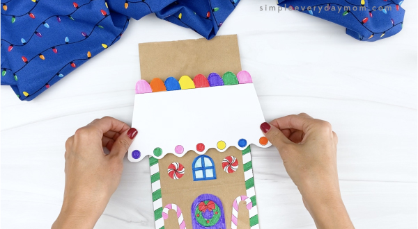 hand gluing gingerbread house roof onto paper bag