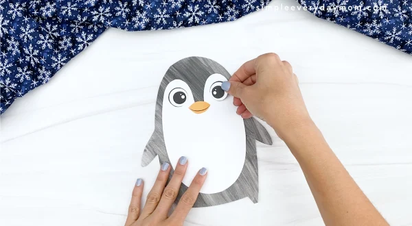 hand gluing eye to printable penguin craft