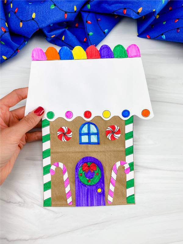 hand holding paper bag gingerbread house