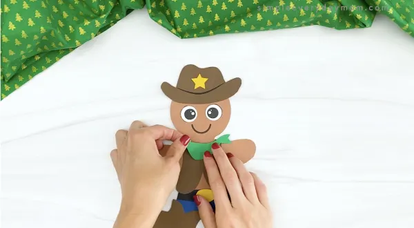 hand gluing bandana onto cowboy gingerbread man