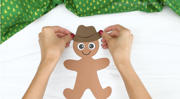 hand gluing hat onto cowboy gingerbread man