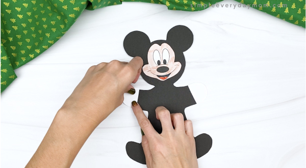 hand gluing gloves onto Mickey gingerbread man craft