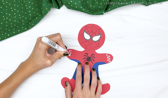 hand drawing icing decorations on spiderman gingerbread craft