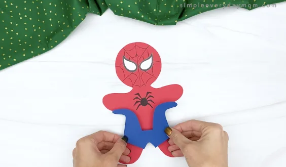 hand gluing blue part to spiderman gingerbread craft