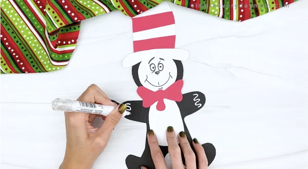 hand drawing icing decorations onto cat in the hat gingerbread man craft