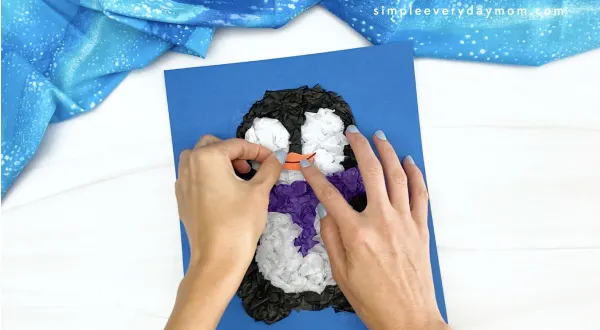hand gluing beak to tissue paper penguin