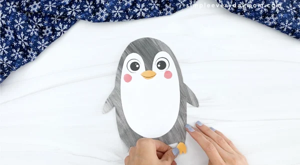 hand gluing feet to printable penguin craft