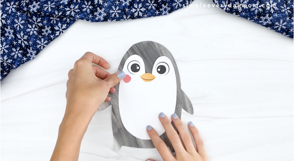 hand gluing cheek to printable penguin craft