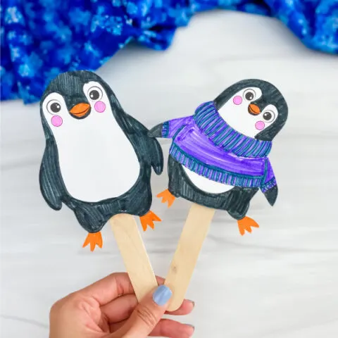 hand holding penguin stick puppets
