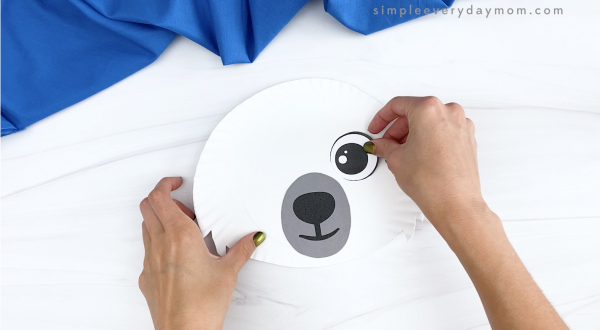 hand gluing eye to paper plate polar bear