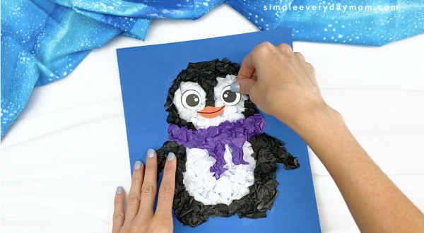 hand gluing eye to tissue paper penguin