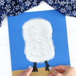 hand gluing feet onto snowy owl craft