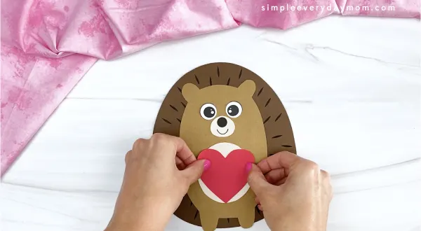 hand gluing heart to hedgehog valentine craft