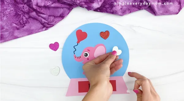 hand placing stickers onto Valentine snow globe craft