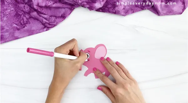 hand drawing cheek onto pink paper elephant