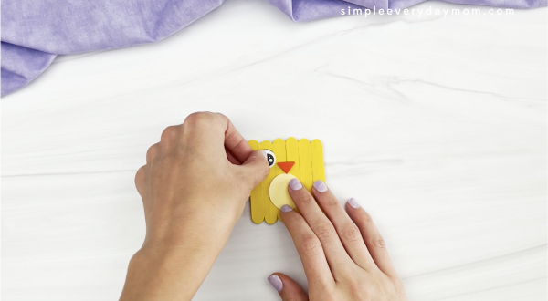 hand gluing wings to popsicle stick chick craft