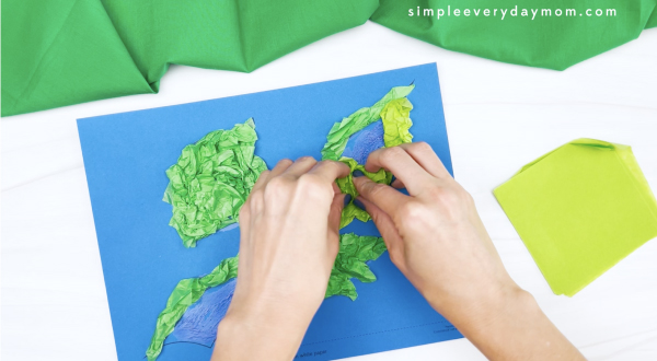 hand gluing tissue paper to dinosaur tissue paper craft
