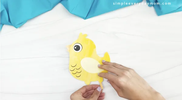 hand gluing foot onto printable chick craft