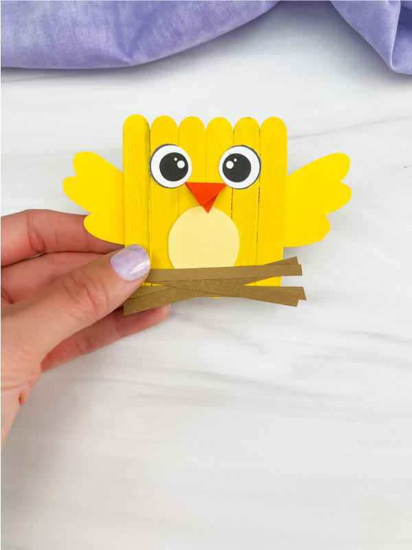 hand holding chick popsicle stick craft