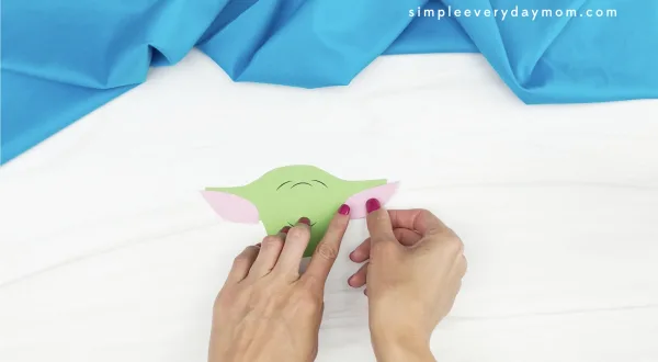 hand gluing inner ear to Baby Yoda handprint craft