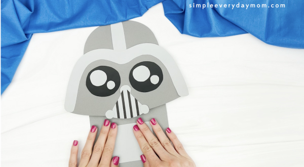 hand gluing panel to Darth Vader paper bag puppet craft
