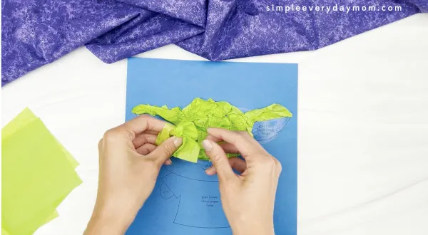 hand gluing green tissue paper to Baby Yoda tissue paper craft