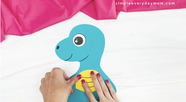 hand gluing belly to dinosaur Mother's Day craft