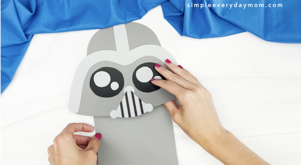 hand gluing body to Darth Vader paper bag puppet craft