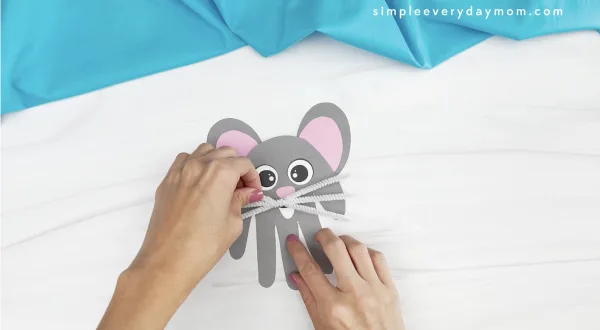 hand gluing whiskers to handprint mouse