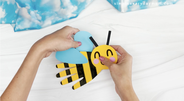 hand gluing wings to handprint bee craft