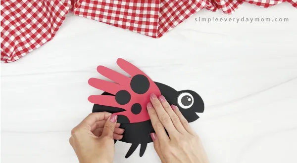 hand gluing wing to handprint ladybug craft template