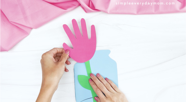 hand gluing flower to handprint flower card craft