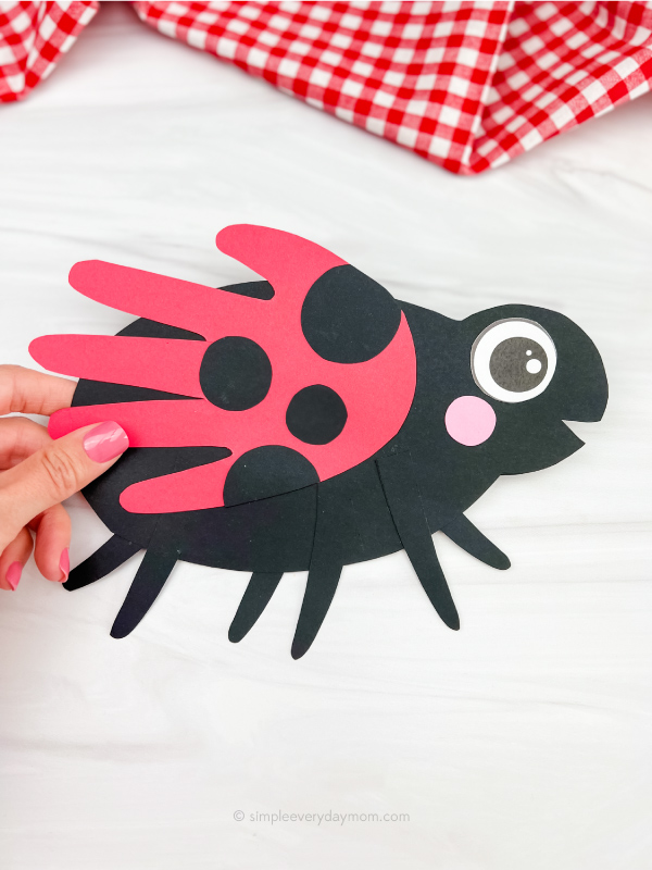 hand holding handprint ladybug craft