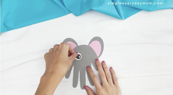 hand gluing eye to handprint mouse