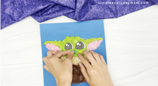 hand gluing nose to Baby Yoda tissue paper craft