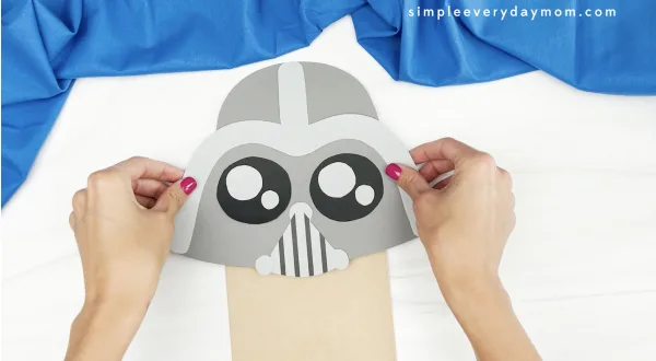 hand gluing helmet to Darth Vader paper bag puppet craft