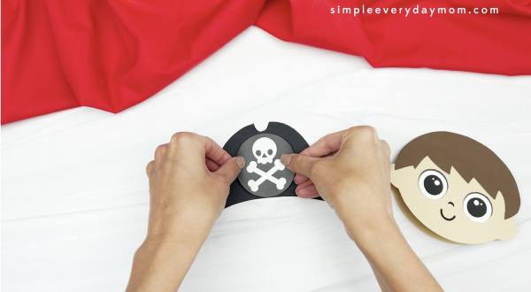 hand gluing skull and crossbones onto pirate hat