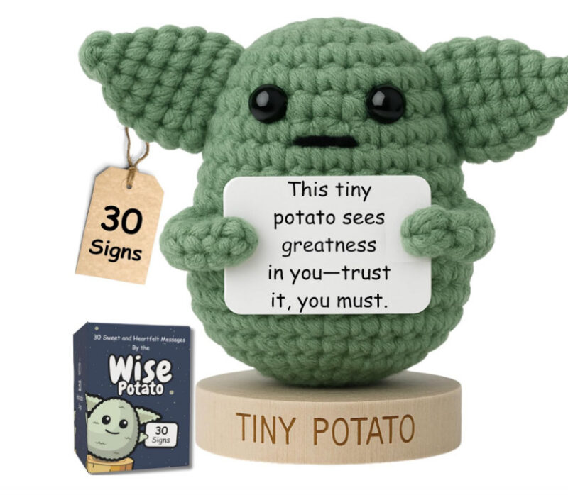 A crochet baby yoda holding an affirmation sign.