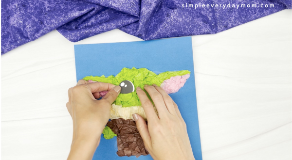 hand gluing eyes to Baby Yoda tissue paper craft