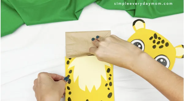 hand gluing body to cheetah paper bag puppet craft