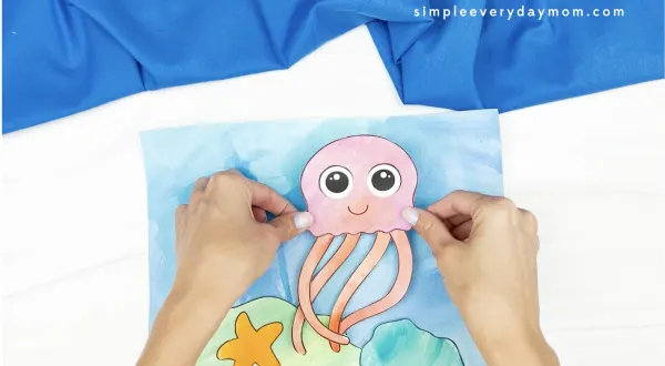 hand gluing jellyfish to jellyfish painting