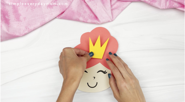 hand gluing crown to princess puppet craft