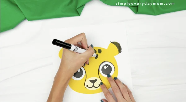 hand drawing spots onto cheetah puppet craft face