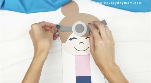 hand gluing head mirror to doctor puppet craft