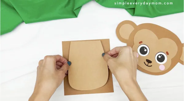 hand gluing belly to monkey puppet craft